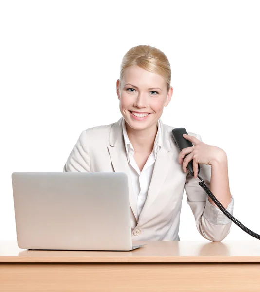坐在办公室桌前用电话听筒的年轻女商人 — 图库照片