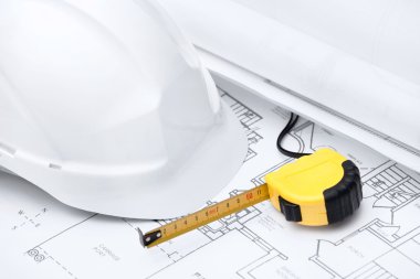 White hard hat and tape measure are on the design druft clipart