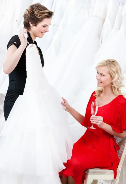 Winkelbediende stelt een bruiloft jurk voor de bruid — Stockfoto