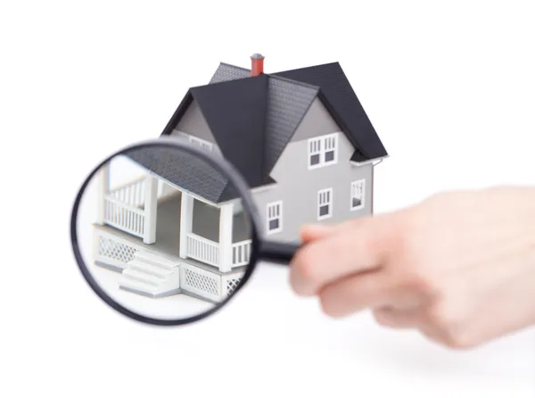Hand holding magnifying glass in front of the home — Stock Photo, Image