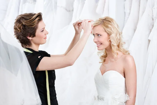 Assistente de loja ajuda a corrigir a tiara do casamento Imagens Royalty-Free