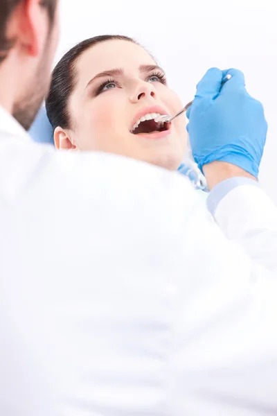 Стоматолог в синих медицинских перчатках осматривает полость рта пациента — стоковое фото