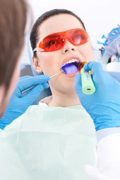 Dentista utilizza lampada fotopolimero per trattare i denti — Foto Stock