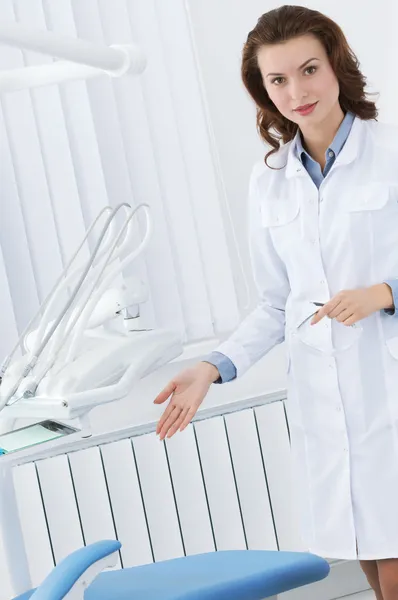 Beautiful assistant points at the dentist's chair — Stock Photo, Image