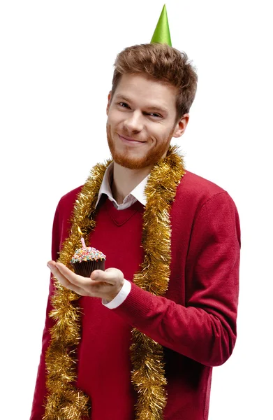 Smiley man with tinsel holds small cake — Stock Photo, Image