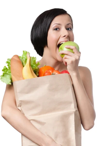 Прекрасна дівчина їсть яблуко і тримає пакет повним здорового харчування — стокове фото