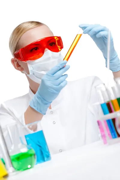 Ženské chemik v respirátor drží lahvičku s oranžovou kapalinou — Stock fotografie
