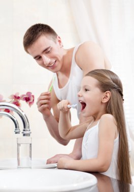Father teachers his daughter to clean teeth clipart