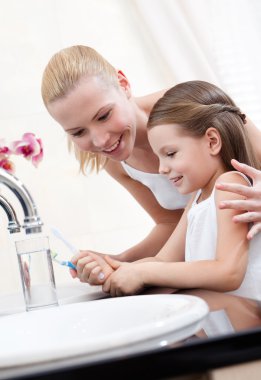 Little girl cleans teeth with her mum clipart