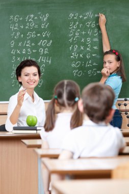 Teacher asks pupils at the chalkboard clipart