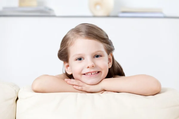 Küçük çocuk beyaz deri kanepeye doğru eğilir. — Stok fotoğraf