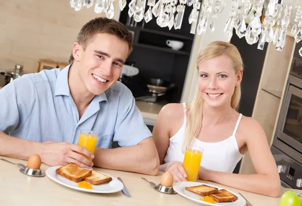 Улыбающаяся пара завтракает на кухне — стоковое фото