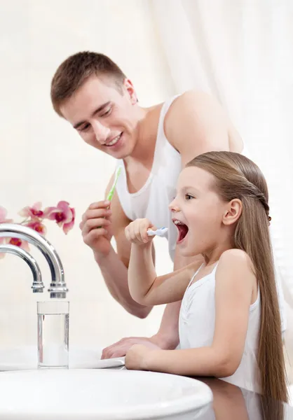 Отец учит свою дочь чистить зубы — стоковое фото