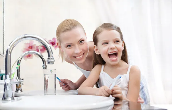 Petite fille brosse les dents avec sa mère — Photo