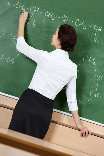 Teacher writes with chalk at the blackboard — Stock Photo, Image