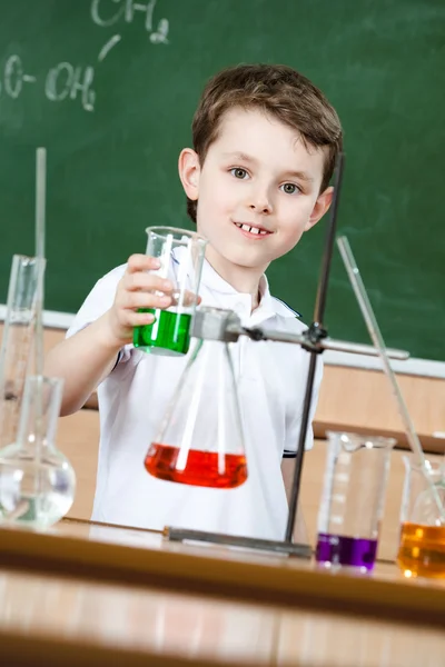 Маленький химик показывает цветную жидкость в конической фляжке — стоковое фото