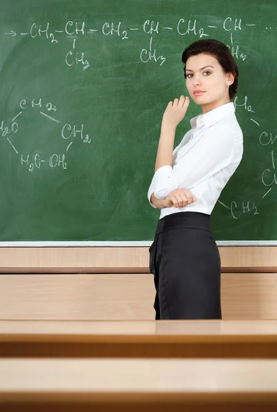 Serious teacher wrote chemical formula at the blackboard — Stock Photo, Image