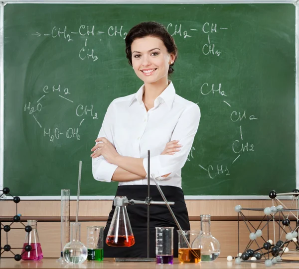 Smiley chemistry teacher is surrounded with chemical glassware — Stock Photo, Image