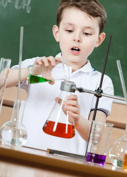 Little chemist pours colored liquid in conical flask — Stock Photo, Image