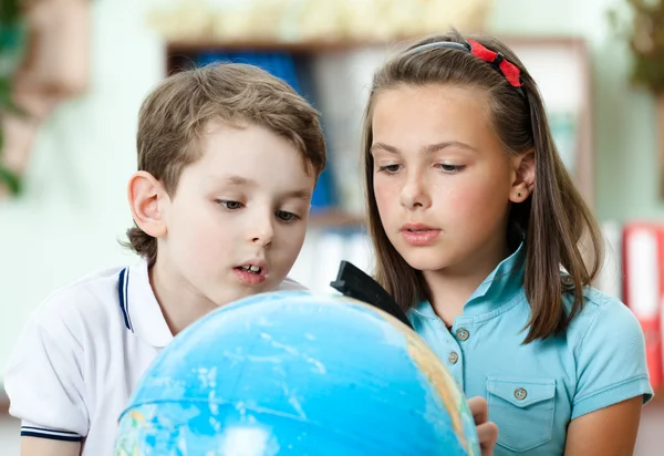 Dois amigos examinam um globo escolar — Fotografia de Stock