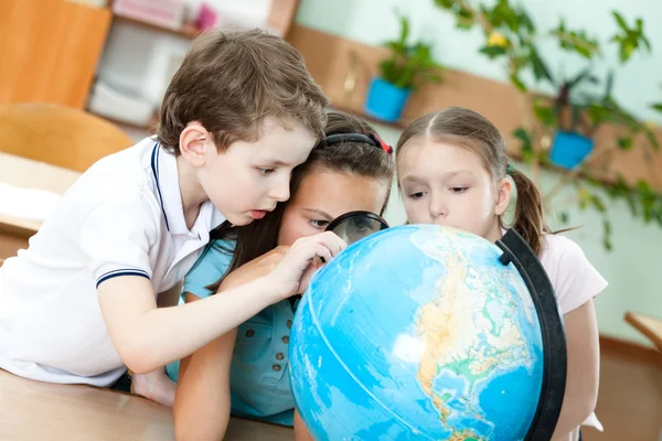 Drie vrienden onderzoeken een school globe — Stockfoto