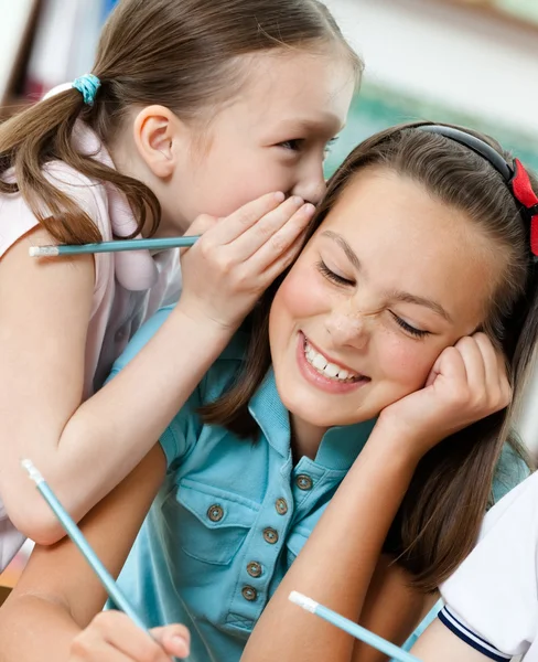 Twee schoolmeisjes fluisteren met elkaar zijn verbonden — Stockfoto