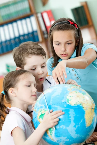Klasskamrater hjälpa varandra att hitta något på globe — Stockfoto