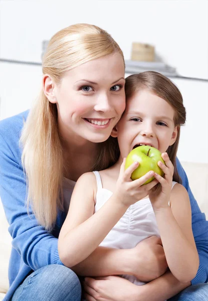 Smiley mum with her eating apple daughter Royalty Free Stock Images