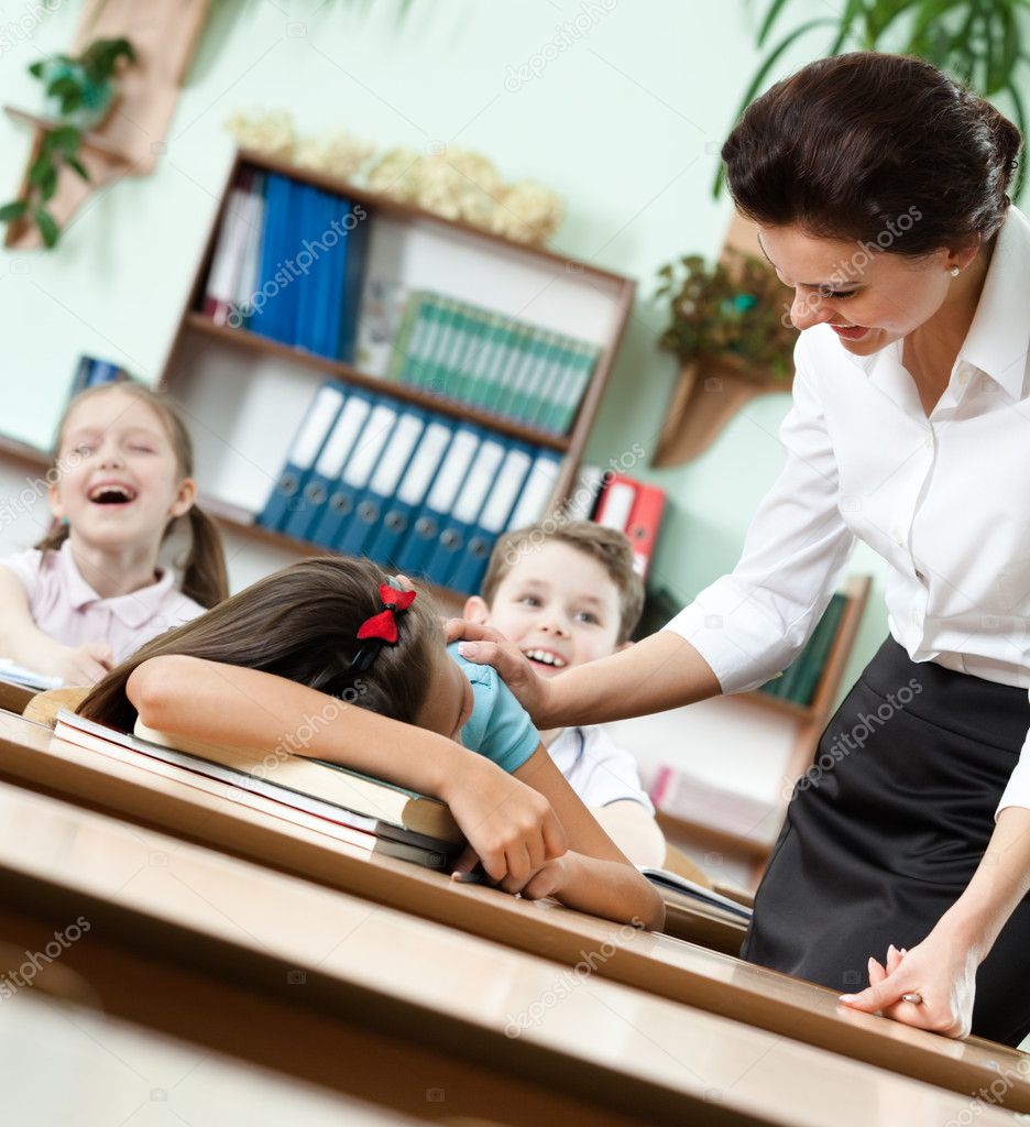 Teacher wakes a sleeping at the desk pupil up