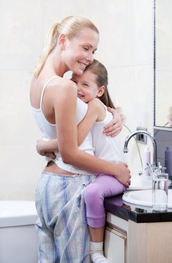 Mother and daughter embrace each other in bathroom clipart