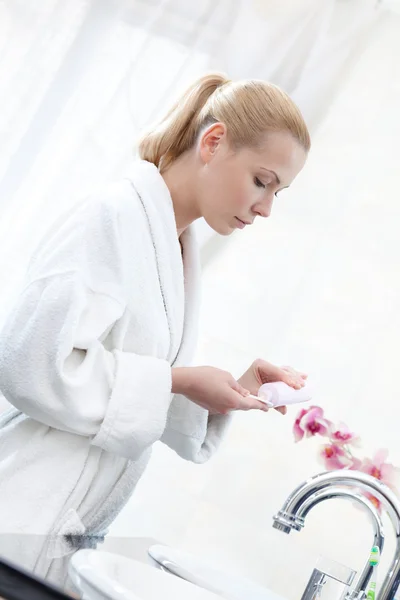 Young lady washes face with lotion — Stock Photo, Image