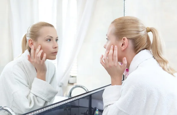 Pretty woman looks at her self in mirror — Stock Photo, Image