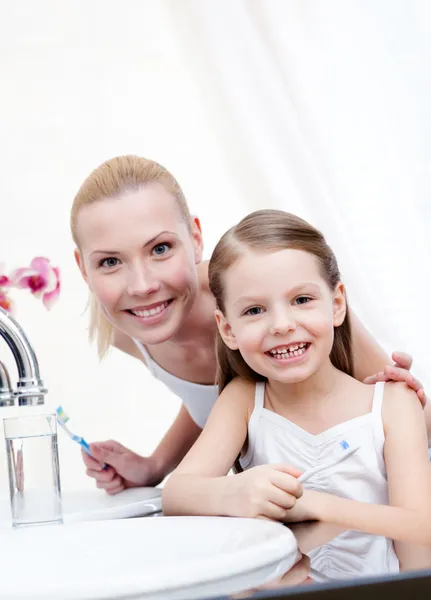 Маленькая девочка чистит зубы со своей мамой — стоковое фото