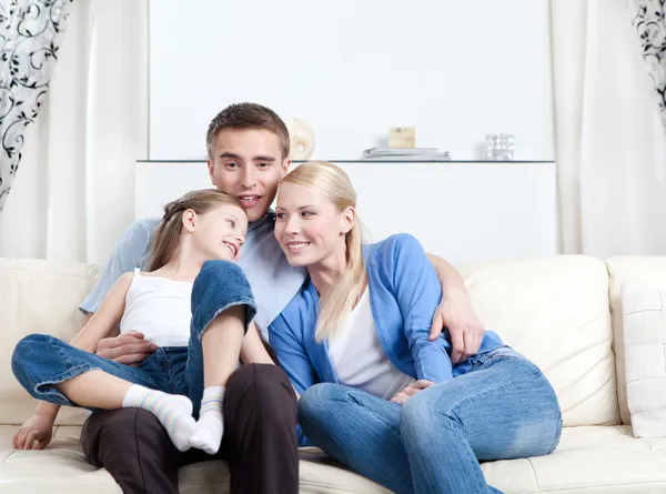 Счастливая семья смеется сидя на диване — стоковое фото