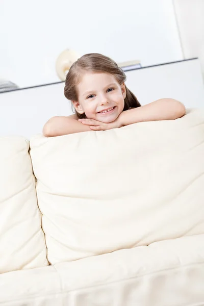 Маленький ребенок наклоняется к дивану — стоковое фото