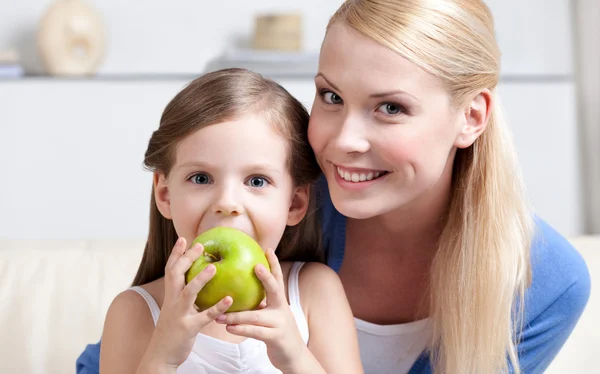 Улыбающаяся мама с яблочной дочкой — стоковое фото