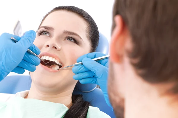 Le dentiste examine la cavité buccale d'une jolie patiente — Photo