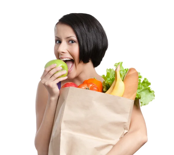 Härlig flicka äter ett äpple, att hålla paketet full av hälsosamma livsmedel — Stockfoto