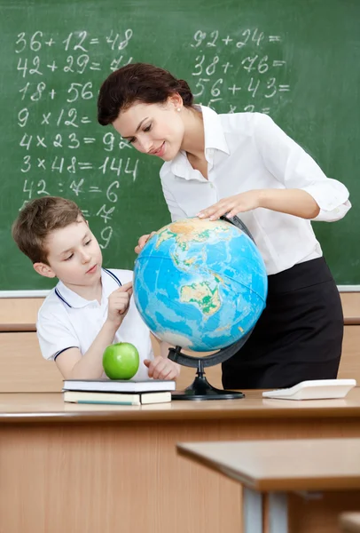 Geography teacher shows something to the pupil at the globe — Stock Photo, Image