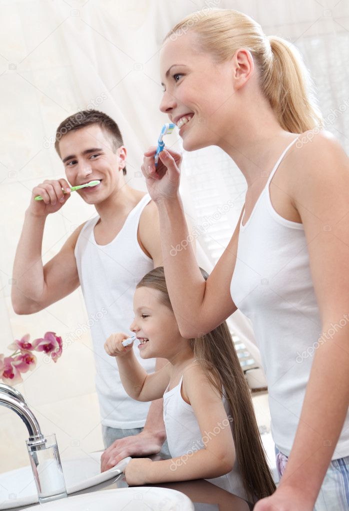 Family of three brush their teeth