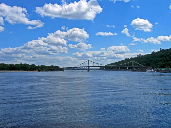 Kładka dla pieszych nad rzeką Dniepr pod chmury cumulus biały, Kijów. — Zdjęcie stockowe