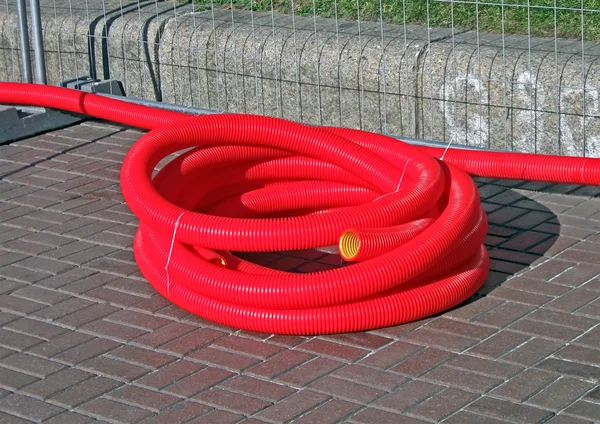 Κόκκινο πλαστικό καλώδιο χύμα στο δρόμο, βιομηχανικό αντικείμενο. — Φωτογραφία Αρχείου