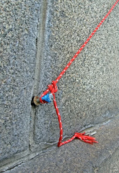 Roter Knoten aus textilem Garn auf Granitwand, Verstärkung. — Stockfoto