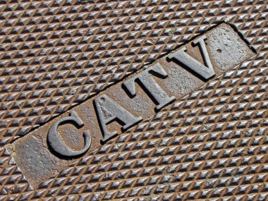 Cable television as text on vintage metal manhole, telecom. clipart