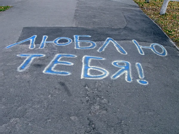 Rakastan sinua, sininen teksti kuin graffiti asfaltilla venäjän kielellä . — kuvapankkivalokuva