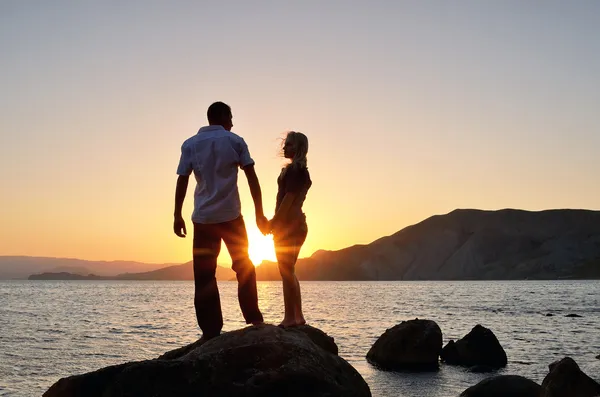 Menino e menina olham um para o outro, de mãos dadas na praia — Fotografia de Stock
