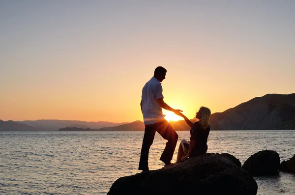 Um homem dá a mão de uma mulher na praia — Fotografia de Stock