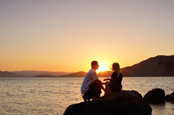 Junges Paar spricht auf einem Felsen am Meer — Stockfoto