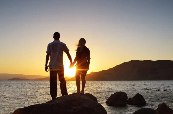 Kız ve erkek el ele tutuşma ve güneş izlerken — Stok fotoğraf