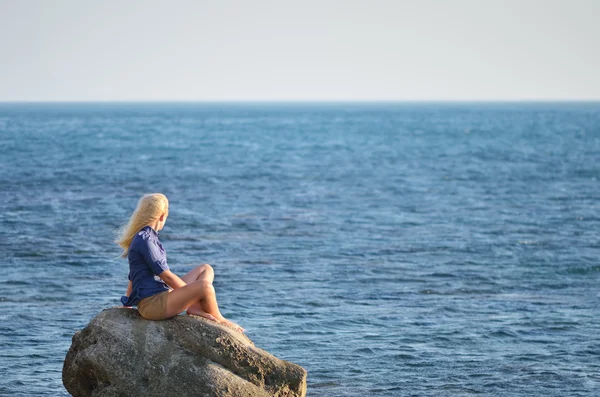 Girl in the blue shirt looks at the sea — Stock Photo, Image
